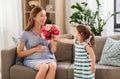 Girl giving flowers to her pregnant mother at home