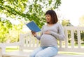 Happy pregnant asian woman reading book at park Royalty Free Stock Photo