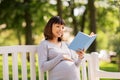 Happy pregnant asian woman reading book at park Royalty Free Stock Photo