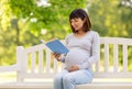 Happy pregnant asian woman reading book at park Royalty Free Stock Photo