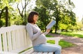 Happy pregnant asian woman reading book at park Royalty Free Stock Photo