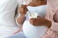 Pregnant woman eating yogurt for breakfast in bed Royalty Free Stock Photo