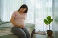 Pregnancy, people rest and expectation concept - Asian smiling happy pregnant woman sitting in bed and touching her belly at home Royalty Free Stock Photo