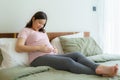 Pregnancy, people rest and expectation concept - Asian smiling happy pregnant woman sitting in bed and touching her belly at home Royalty Free Stock Photo