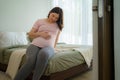 Pregnancy, people rest and expectation concept - Asian smiling happy pregnant woman sitting in bed and touching her belly at home Royalty Free Stock Photo