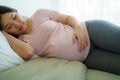 Pregnancy, people rest and expectation concept - Close up of smiling happy pregnant woman lying in bed and touching her belly at Royalty Free Stock Photo