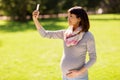 Happy pregnant asian woman taking selfie at park Royalty Free Stock Photo