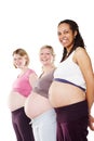 Pregnancy pose. Three pregnant women standing in a row smiling at the camera with their stomachs exposed.