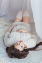 Pregnancy, rest, and expectation concept - close up of happy smiling pregnant woman lying in bed covered with canopy and