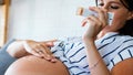 Pregnancy, skin care and maternity concept. Pregnant woman applying stretch mark cream to belly Royalty Free Stock Photo