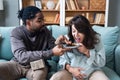 Pregnancy support and fun. Young couple man and pregnant woman sitting at home teasing with sweet food forbidden by doctor. Male Royalty Free Stock Photo