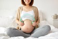 Happy pregnant woman with headphones at home