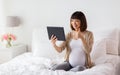 Happy pregnant asian woman with tablet pc at home Royalty Free Stock Photo
