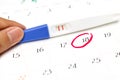 Pregnancy test with positive result lying on calendar background. Royalty Free Stock Photo