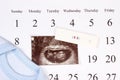Pregnancy test, ultrasound scan of baby and clothing for newborn on calendar, concept of expecting for baby Royalty Free Stock Photo