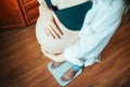 Pregnancy weight gain woman. Happy pregnant woman standing on weight scales. Therapy, healthcare, motherhood concept. Royalty Free Stock Photo