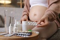 Pregnancy wellness. Maternal medication and motherhood. Unrecognizable pregnant woman with bare belly taking pills or medicine Royalty Free Stock Photo