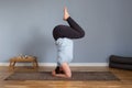 Pregnant woman doing exercises standing in a yoga pose headstand on her head.