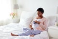 Pregnant african woman with baby bootees in bed