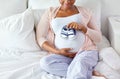 Pregnant african woman with baby bootees in bed