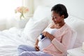 Pregnant african woman with baby bootees in bed