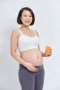 Pregnant asian people standing on white room, she drinking fresh orange juice, she use her hand holding a glas Royalty Free Stock Photo