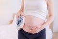 A pregnant Asian woman stands in her bedroom and prepares a small pair of shoes for her child Royalty Free Stock Photo
