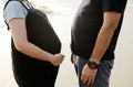 Pregnant Asian woman wife and husband with a belly are happy and standing on the sand beach together. Family love trip in summer Royalty Free Stock Photo