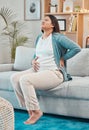 Pregnant, back pain and woman with ache and body strain while sitting on her living room sofa. Belly, anatomy and Royalty Free Stock Photo