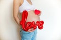 Pregnant belly with balloon love on a light background. The joy and happiness of motherhood. Copyspace Royalty Free Stock Photo