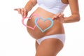 Pregnant belly with blue and pink heart. Horizontal closeup.