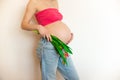 Pregnant belly with a bouquet of flowers. The joy and happiness of motherhood pregnant girl in anticipation of the baby