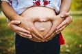 Pregnant Belly with fingers Heart symbol. Beautiful Young Pregnant Woman and Her Husband Together Caressing Her Pregnant Belly. Royalty Free Stock Photo