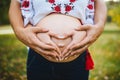 Pregnant Belly with fingers Heart symbol. Beautiful Young Pregnant Woman and Her Husband Together Caressing Her Pregnant Belly. Royalty Free Stock Photo