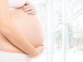 Pregnant belly of a young woman in a light interior Royalty Free Stock Photo