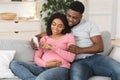 Pregnant black couple using smartphone together at home Royalty Free Stock Photo