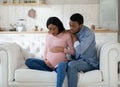 Pregnant black woman feeling pain, giving birth to child, having contractions while husband calling doctor on phone Royalty Free Stock Photo