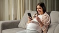 Brunette pregnant woman pays for online shopping via phone Royalty Free Stock Photo