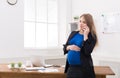 Pregnant business woman talking on phone at office Royalty Free Stock Photo