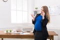 Pregnant business woman talking on phone at office Royalty Free Stock Photo