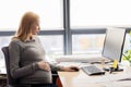 Pregnant businesswoman with computer at office