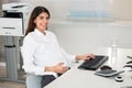 Pregnant Businesswoman Using Computer At Desk In Office Royalty Free Stock Photo