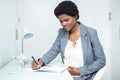 Pregnant businesswoman writing on notebook Royalty Free Stock Photo