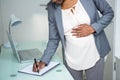 Pregnant businesswoman writing on notebook Royalty Free Stock Photo