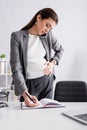 pregnant businesswoman writing in notebook and Royalty Free Stock Photo