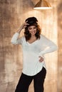 Pregnant european woman in white blouse and black pants with a black hat in dark flat, stylish and happy pregnant woman