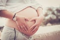 Pregnant caucasian young woman do hearth sign for love concept on his beautiful big belly - people and future concept life with