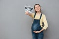 Pregnant cheerful woman holding ultrasound scans.