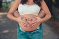 Pregnant couple forming a heart shape with their hands on the woman& x27;s belly Royalty Free Stock Photo