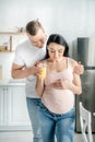 Pregnant couple hugging and holding orange juice in kitchen Royalty Free Stock Photo